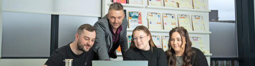 Employees discuss something on a computer screen