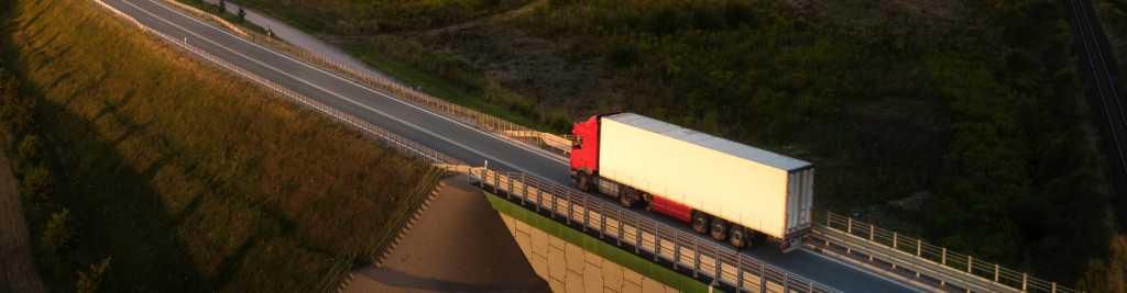 A photo of a truck and trailer driving across a bridge